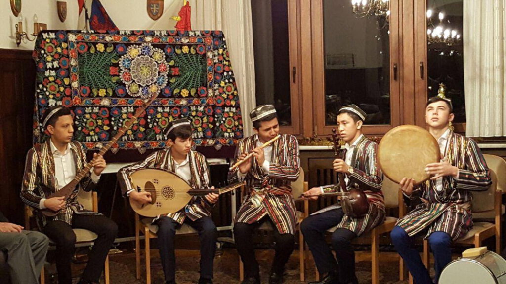 Weihnachtsfeier 2016 Junge Männer in zentralasiatischen Trachten spielen traditionelle Instrumente (dutar, Oud, Flöte, Rahmentrommel) vor bunter bestickter Wanddecke