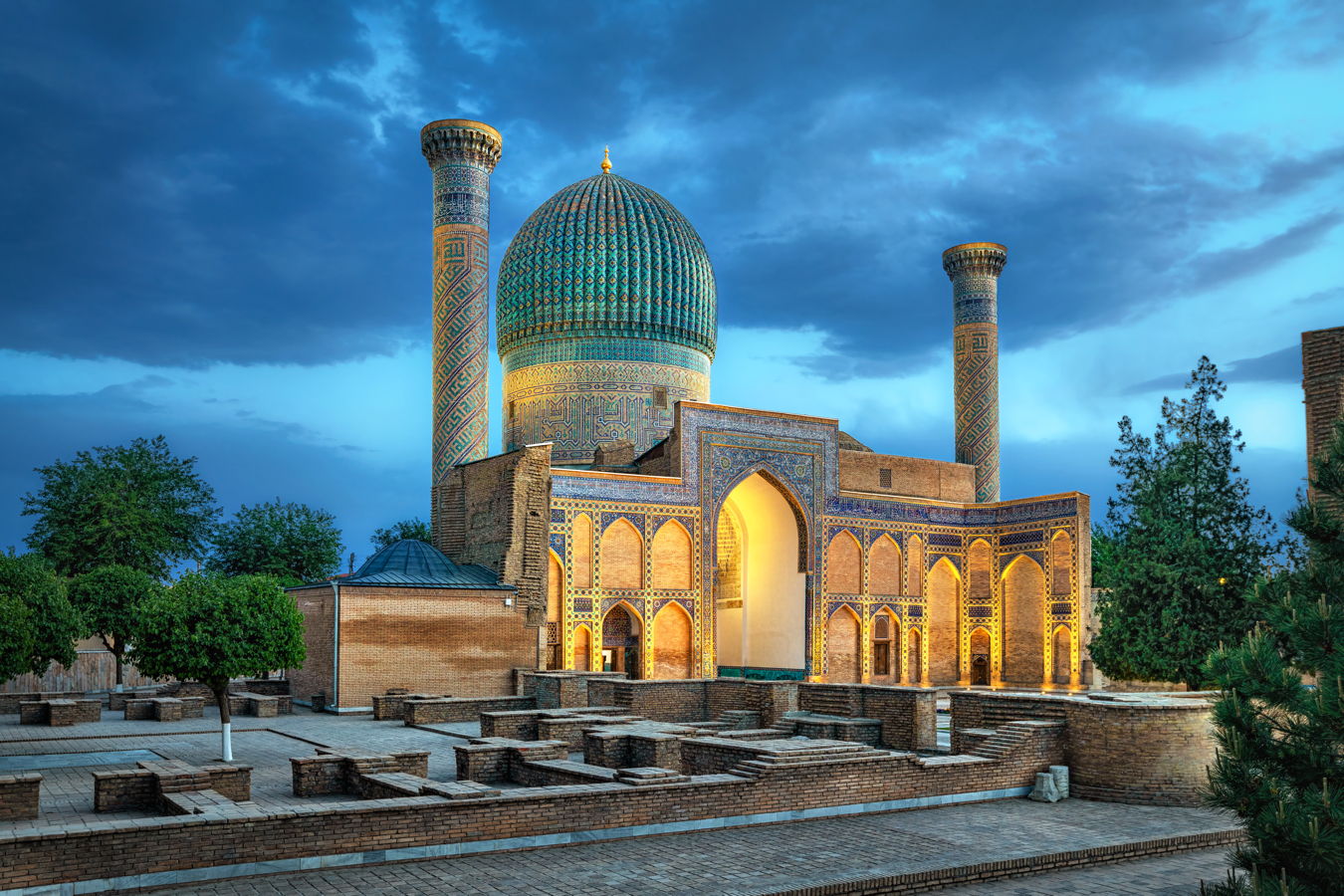 Historische Moschee mit großer türkis gefliester Kuppel und zwei verzierten Minaretten bei Abenddämmerung, Samarkand-Architektur, orientalische Mosaike