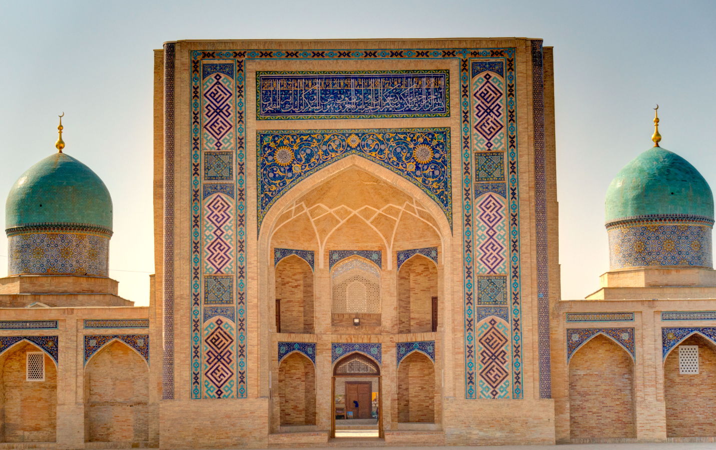 Moscheeportal mit blauen Kuppeln und detaillierten islamischen Kachelornamenten an einem historischen Gebäude in Zentralasien