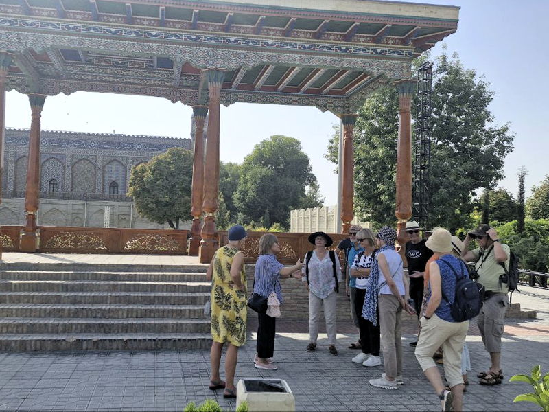 kokan reise Eine Reisegruppe steht vor einem reich verzierten Pavillon im Freien