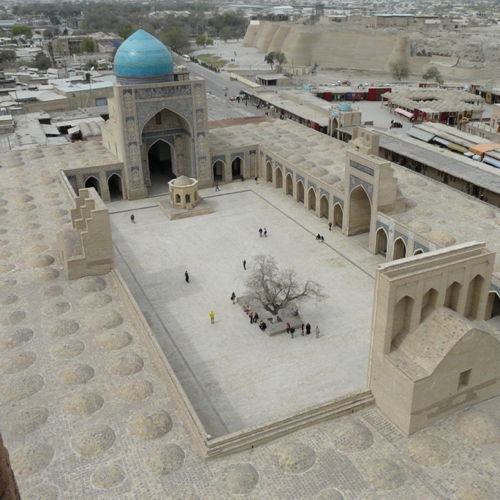 Usbekistan Reise 4.-14.10.2027 Blick auf einen Innenhof einer Moschee mit blauem Kuppelturm und wenigen Menschen