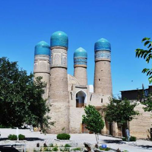 Usbekistan Reise 26.04. – 6.05.2027 Historische Moschee mit vier türkis gekachelten Kuppeltürmen unter blauem Himmel